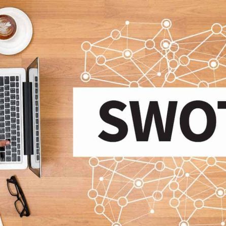 mesa-de-madeira-com computador-e escrito swot na mesa