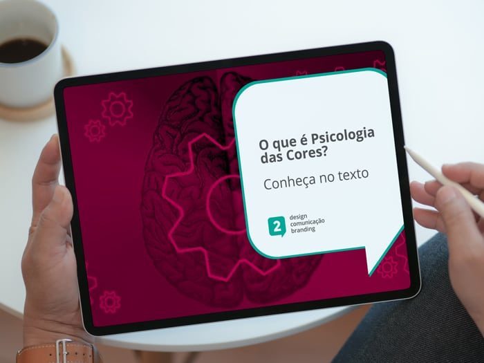 Imagem pessoa segurando um tablet, na tela um desenho sobre marketing sobreposto de um filtro rosa com o descritivo "O que é Psicologia das Cores? Conheça no texto"