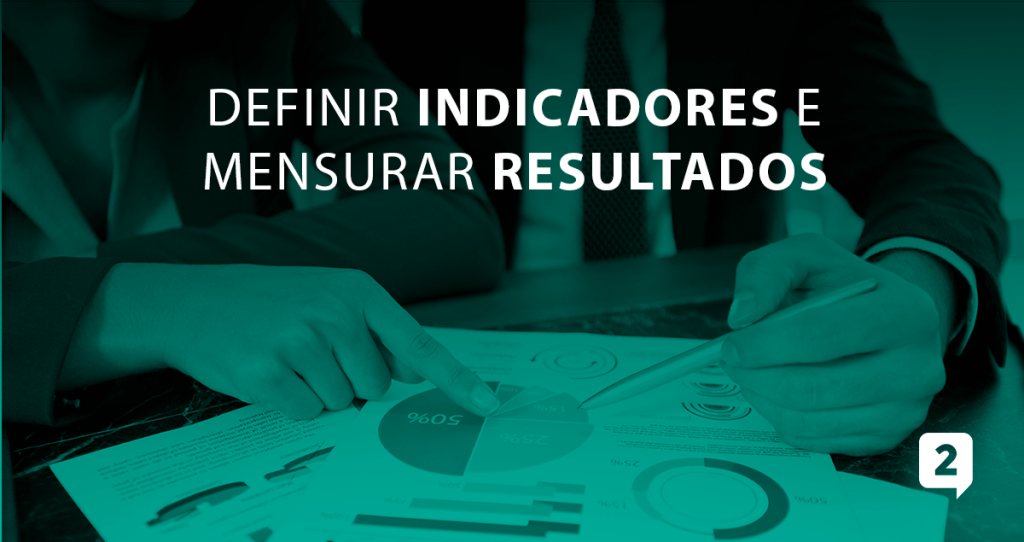 Duas pessoas analisando gráficos em uma mesa com o seguinte título na imagem: "Definir indicadores e mensurar resultados"