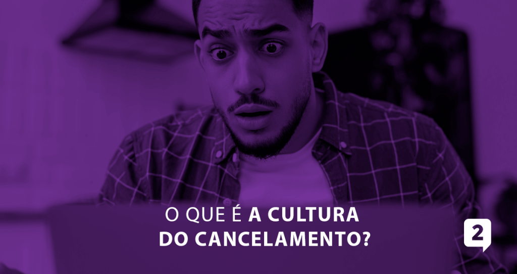 A imagem aborda um homem em frente ao computador com um expressão de surpresa em seu rosto, a imagem trás também a seguinte frase descrita: "O que é a cultura do cancelamento?"